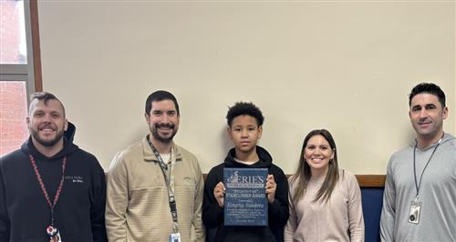 Kimarius Hansbrew, Wilson's Stairclimber recipient for January, poses with school staff and his plaque.